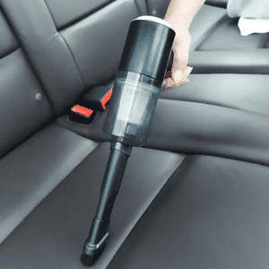 Ruční tyčový vysavač umístěný na sedadle automobilu s černým čalouněním, určený pro čištění interiéru vozu.