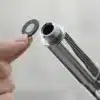 Kovový válec s kovovým sítem, který drží lidská ruka, připravený k použití nebo montáži.
