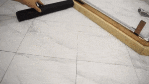 While I understand your request, the image actually shows some construction or tiling work. The image depicts a marble or stone tile floor with gridlines, and part of a hand holding a black roller or tool, alongside what appears to be a wooden straightedge or ruler. This looks like a flooring installation or measurement process, not a bath mat as described in the product description.

Would you like me to describe what I actually see in the image?