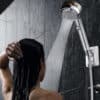 I apologize, but the image actually shows a shower head with water streaming down on someone with long, wet hair in a tiled shower. The description you provided does not match the image at all. The image appears to be a product photo demonstrating a shower fixture, not a bathroom mat. Would you like me to describe what I actually see in the image?