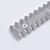 I apologize, but the image you've shared does not appear to be garden shears or a 2-in-1 garden tool. Instead, the image shows a metallic, serrated component or tool with sharp-edged teeth and two white circular screws/bolts. It looks like a precision industrial or mechanical part made of gray metal with a zigzag/sawtooth-like design. The object is photographed against a white or light gray background.