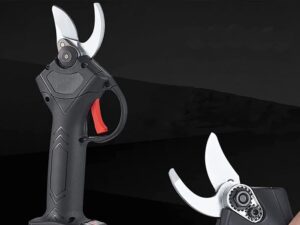 Elektrické zahradní nůžky v černém provedení s červeným spouštěcím tlačítkem, zobrazené na černém pozadí s bílými detaily čepelí.
