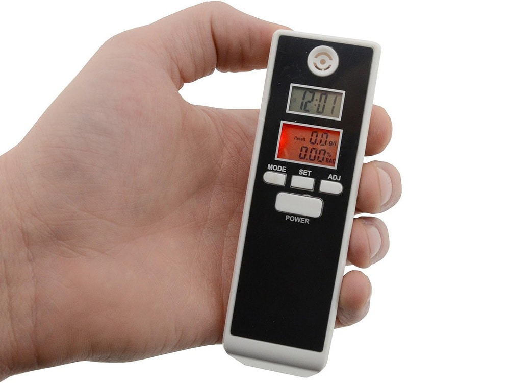 Digitální alkohol tester s LCD displejem, který je držen v ruce a umožňuje rychlé změření hladiny alkoholu v dechu.