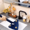 The image shows a modern kitchen sink area with a unique triangular blue mop and some decorative items like a yellow vase with flowers in the background.