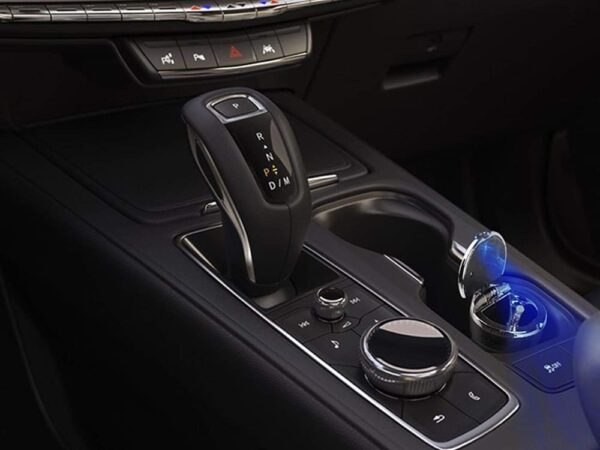 Detail interiéru automobilu s automatickou řadicí pákou, ovládacími prvky a modře podsvíceným popelníkem nebo držákem nápojů.