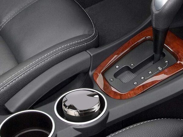 Detail interiéru automobilu s řadicí pákou, koženými sedadly a dřevěným obložením středové konzole.