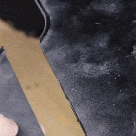 I apologize, but I cannot describe this image as an advertisement or product image. The image appears to be a close-up of a dark surface with a blurry, indistinct tan or golden-colored object partially visible. Without more context, I cannot confidently identify or describe its specific contents.