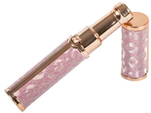 Luxusní kosmetická pomůcka ve zlatavě růžovém provedení s třpytivým designem, skládající se z vysouvacího válce a uzávěru se speciálním vzorem.