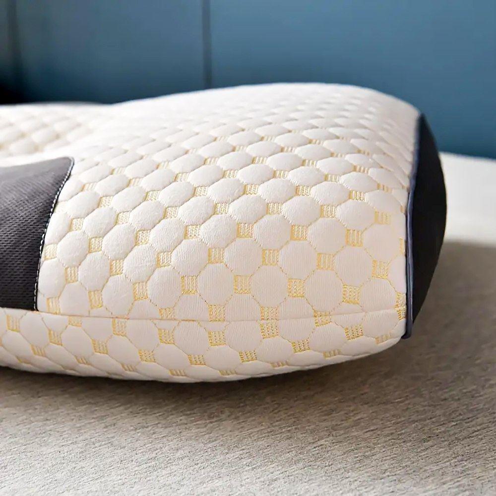 Ergonomický masážní polštář s reliéfním povrchem v bílé barvě se zlatými detaily, určený pro podporu krku a relaxaci.