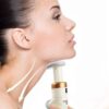 Žena v profilu používající přístroj na péči o pleť, který je namířen na oblast krku a brady, s graficky znázorněnými skincare tahy.