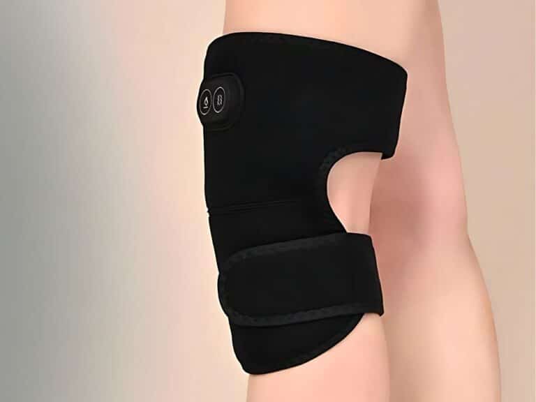 Černá ortéza na koleno s technologickým designem, připevněná na světlém pozadí zobrazující část lidské nohy.