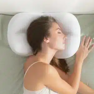 Bílý ergonomický polštář ve tvaru mraku, na kterém spí žena s zavřenýma očima, podporující správné držení hlavy a krku během spánku.