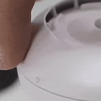 Detail bílé elektrické varné konvice s patrným profilem jejího víka a oblého těla v jemných šedivých tónech.