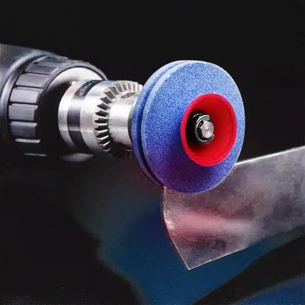 Brusný kotouč modré barvy s červeným středem nasazený na vřeteno elektrického nářadí, určený pro broušení nebo ostření kovových povrchů.