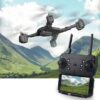 Mini drone with HD camera flying over a mountainous landscape, controlled by a handheld remote with a display screen showing the drone's aerial view.