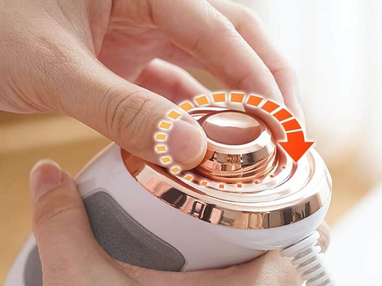 Ruka otáčí bílým a měděně lesklým zařízením s kruhovým indikátorem, který ukazuje postup pomocí oranžových čtverečků a šipky.