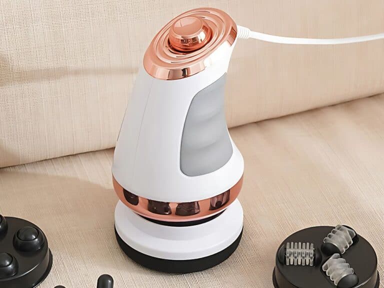 Elektrický masážní přístroj v bílo-měděné barvě s ergonomickým designem a vyměnitelnými nástavci, umístěný na dobíjecí stanici.