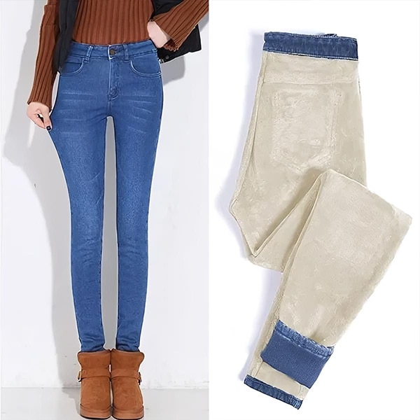 Modré elastické džíny se světle béžovou podšívkou, kombinované s hnědými kotníkovými botami na bílém pozadí.