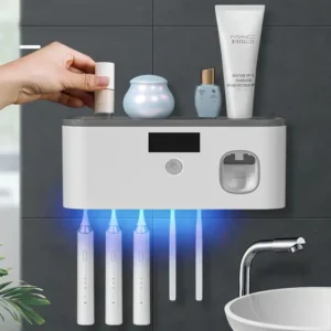 Elektrický držák na zubní kartáčky s UV sterilizací a dávkovačem zubní pasty, umístěný na šedé koupelnové stěně s kosmetickými přípravky a elegantním designem.