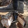 Dřevorubecká bota šlapající na hydraulický štípač dřeva, který rozštípává kládu na menší kusy pomocí šroubovitého mechanismu.