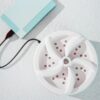 Přenosná USB mini pračka v bílé barvě s modrým napájecím kabelem, složená z několika dílů s malými body, určená pro praní menšího množství oblečení na cestách nebo doma.
