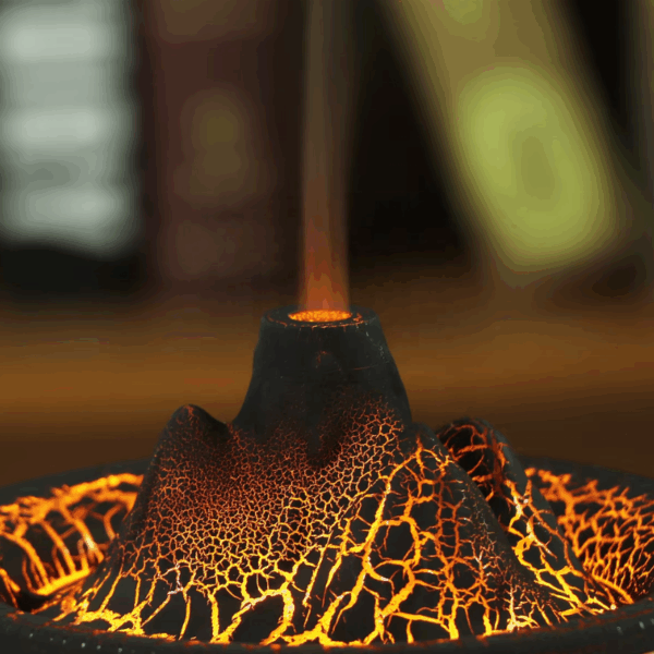 Detail hořící svíčky v designovém kovovém svícnu s praskavým povrchem ve zlatohnědých odstínech, který připomíná tekoucí lávu.