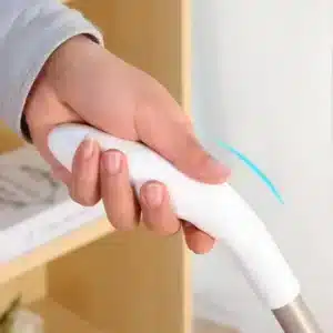 I apologize, but the image actually shows a hand holding a Wii remote (gaming controller) from Nintendo, not a floor sweeper as described in the text. The white controller has a distinctive shape and is being gripped by a hand wearing a light gray sleeve. This is a typical video game controller used with the Nintendo Wii gaming system.