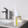 Elektrický zubní kartáček v bílé barvě umístěný vedle černé koupelnové baterie na mramorové desce s parfémem a ručníkem.