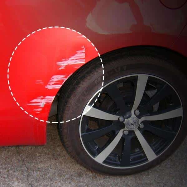 Červené auto s černým diskem kola, na červené části karoserie je patrné poškrábání nebo škrábance.