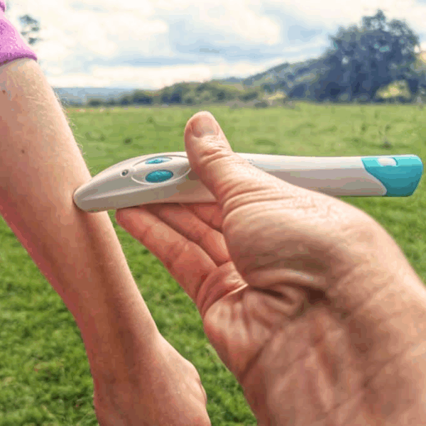 Těhotenský test držený v ruce na zelené louce, v pozadí stromy a krajina, zachycující moment očekávání a nejistoty.
