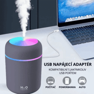 Šedý USB zvlhčovač vzduchu H2O s duhovou LED indikací, který lze napájet z počítače, powerbabanky nebo auta, s výstupem jemné mlhy vedle notebooku.