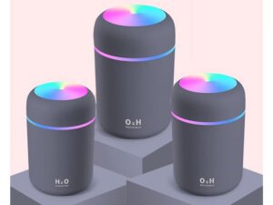 Tři šedé válcovité zvlhčovače vzduchu H2O značky O&H s barevným LED osvětlením v modro-fialových tónech, umístěné na šedých čtvercových podstavcích.