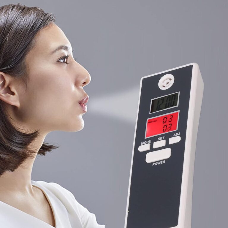 Žena fouká do digitálního přístroje, který pravděpodobně měří výdechový vzduch nebo provádí dechový test.