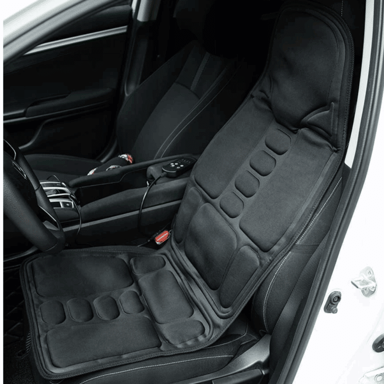 Černá masážní sedačka do auta s ergonomickými polštářky, připojená k sedadlu řidiče v bílém voze a propojená s elektrickým adaptérem.