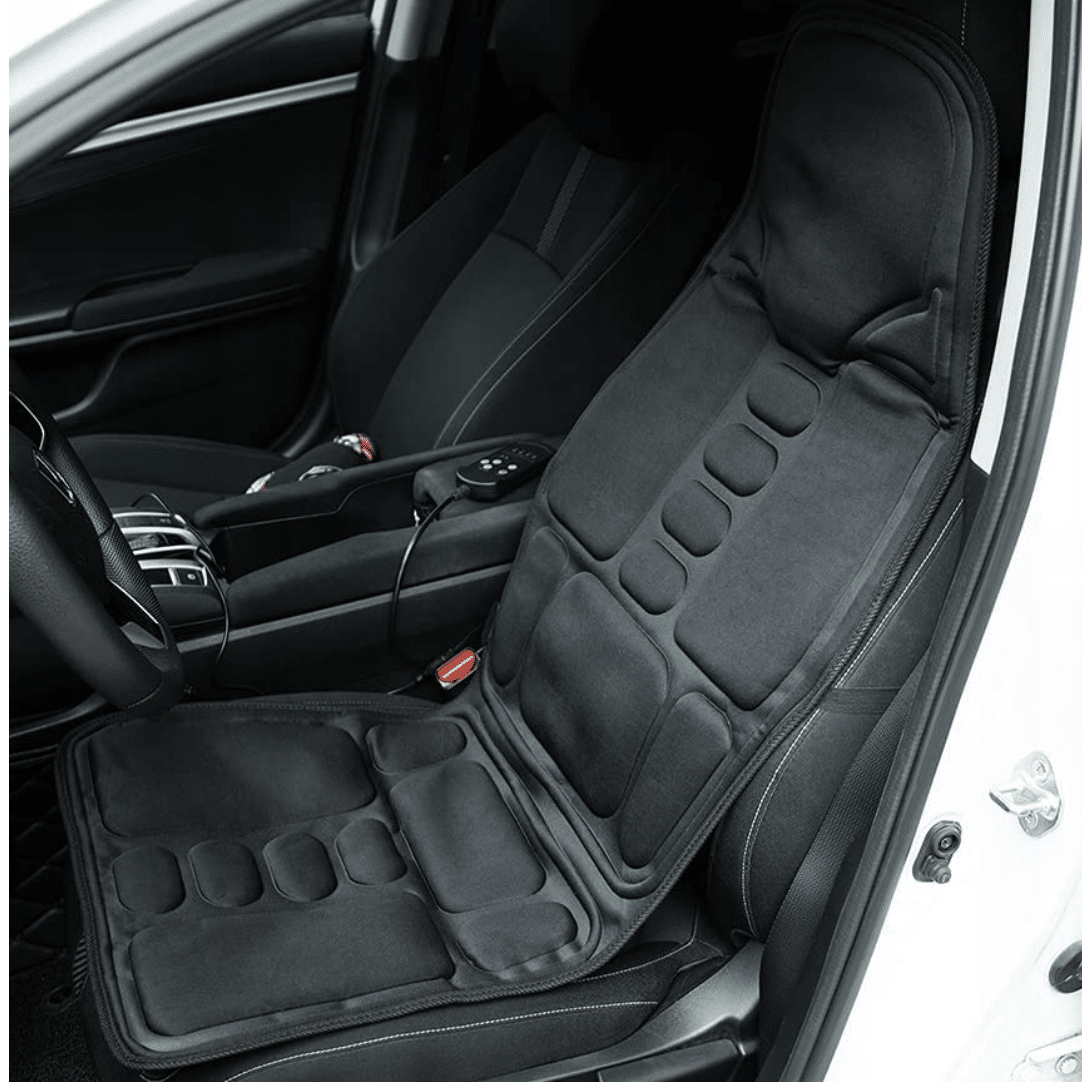 Černá masážní sedačka do auta s ergonomickými polštářky, připojená k sedadlu řidiče v bílém voze a propojená s elektrickým adaptérem.