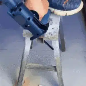Svěrák s kovovým rámem, na kterém je upevněna rukojeť elektrického nářadí připravená k řezání nebo broušení materiálu.