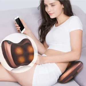 Žena sedící na gauči s mobilem v ruce a masážním polštářem, který používá k uvolnění svalů a relaxaci.