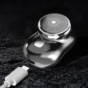 Stříbrný elektrický holicí strojek s kruhovým nástavcem a bílým USB nabíjecím kabelem, umístěný na černém strukturovaném pozadí.