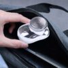Stříbrná kulová elektrická holicí hlava v průhledném pouzdře, kterou drží ruka v šedém textilním prostředí.