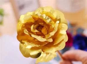 Zlatožlutá umělá nebo dekorativní růže s mnoha vroubkovanými okvětními lístky, která vypadá jemně a plasticky.