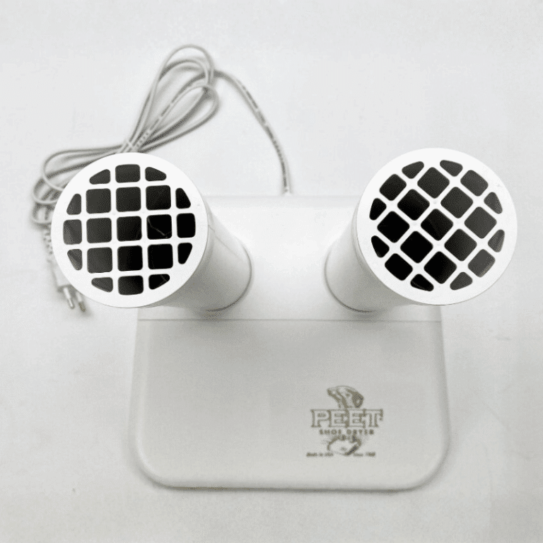 Bílé reproduktory v designu s mřížkou, propojené šedým kabelem a umístěné na podložce s logem Peegt Mobily.