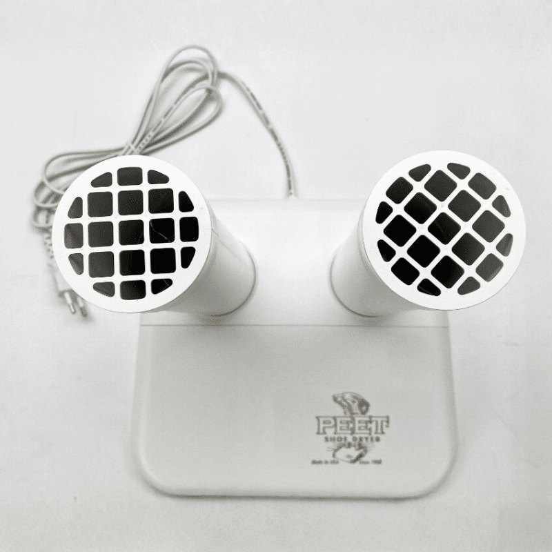Bílé reproduktory v designu s mřížkou, propojené šedým kabelem a umístěné na podložce s logem Peegt Mobily.