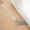 Čisticí mop s dlouhou tyčí stíírající prach nebo nečistoty podél stěny a dřevěné podlahy.