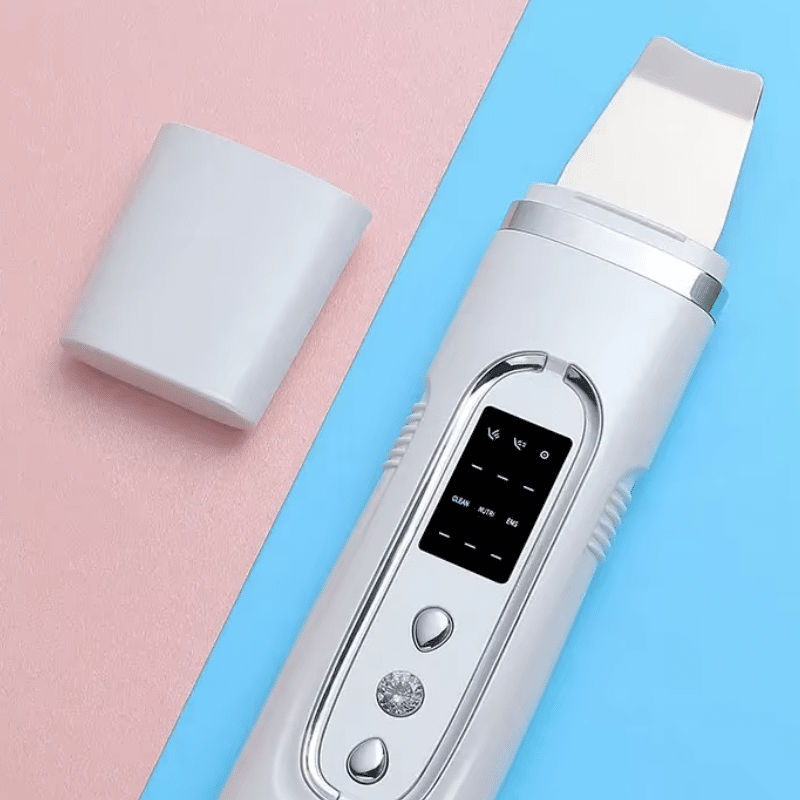 Bílý ultrazvukový čistič pleti s digitálním displejem a příslušenstvím na barevném modro-růžovém pozadí.