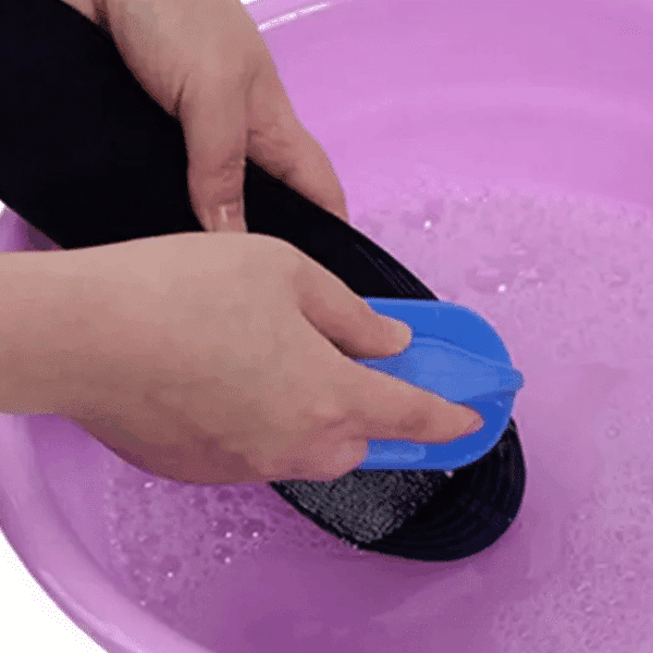 Ruka používá modrý leštící kotouč na černý povrch v fialovém prostředí, pravděpodobně při procesu čištění nebo leštění.